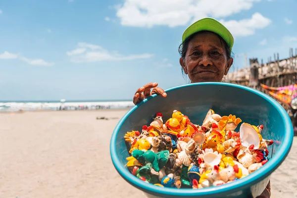 絵の貝殻で作られた手工芸品でいっぱいのボウルを表示するビーチの高齢者ラティーナ通りのベンダー — ストック写真