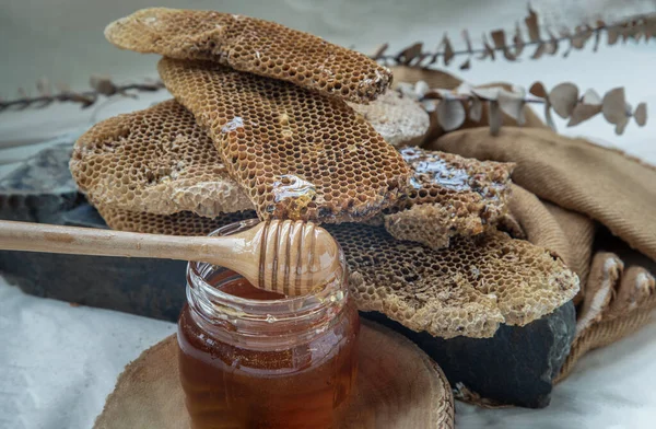 在蜂蜜玻璃瓶上贴上伍登蜂蜜搅拌器棒的新鲜蜂窝 — 图库照片