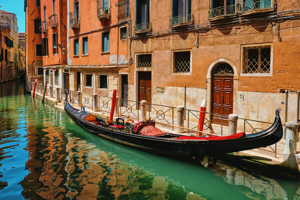 "Narrow canal with gondola in Venice, Italy"