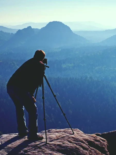 旅游指南和照片爱好者一起三脚架上悬崖和思维 在下面的美丽山谷梦幻般顽固景观 蓝色朦胧日出 — 图库照片