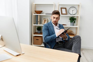 Yönetici, büro yöneticisinin masasındaki belgelere yazıyor.