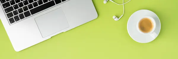 Banner of metallic laptop keyboard, white earphones and coffee cup on light green background