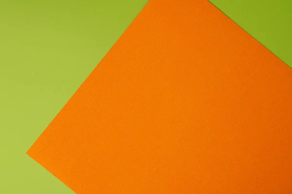 Orange and green colored background of layered cardboard sheets, top view, copy space