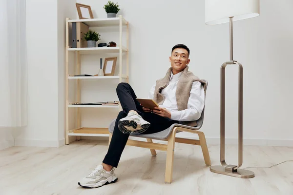 stock image Asian man in the room with the tablet in the chair 