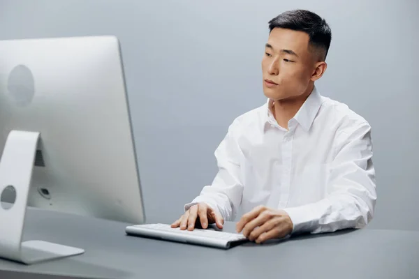白いシャツを着たアジア人男性がコンピュータで働いています — ストック写真