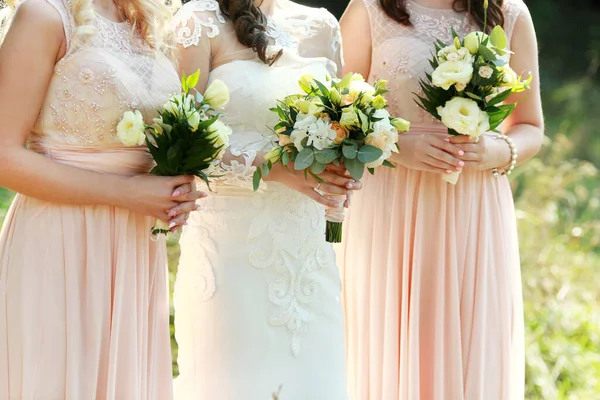 花嫁と新婦付添人は結婚式の花束を手に持って — ストック写真