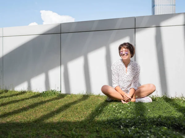 Uśmiechnięta Kobieta Kolorowych Okularach Odpoczywa Trawniku Miejskim Parku Natura Mieście — Zdjęcie stockowe