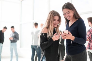 Akıllı telefon ekranına bakan iki genç meslektaş