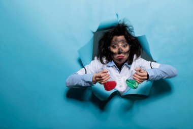 Aptal yüz ifadesi olan çılgın bir kimyager kameraya bakarken deney amaçlı sıvı serumla dolu cam kavanozlar tutuyor..