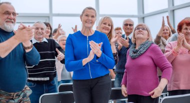 Bir grup yaşlı insan bir çemberin içinde oturup alkışlıyorlar.