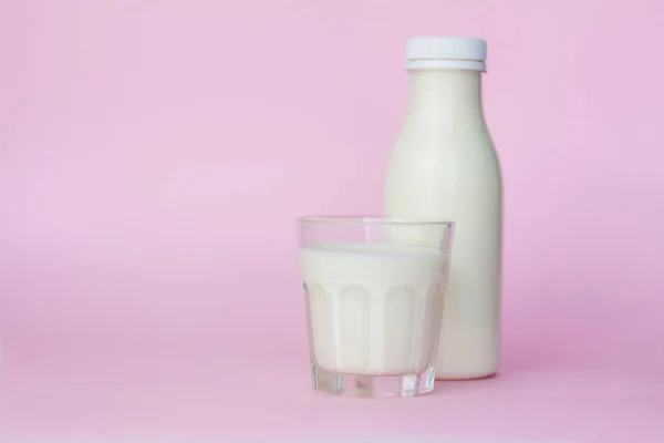 ピンクの背景に強調されたボトルと白いミルクのガラス クローズアップ — ストック写真