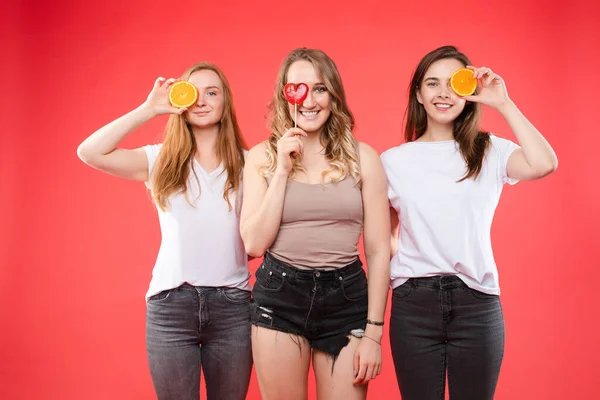 三个快乐的女孩与橘子和甜糖果 — 图库照片