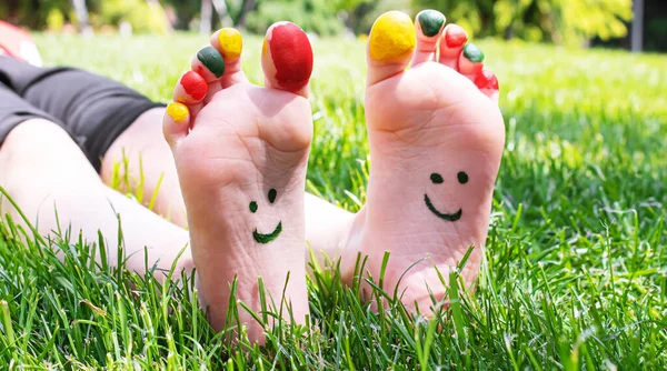 Children\'s feet with a pattern of paints smile on the green grass. Selective focus.