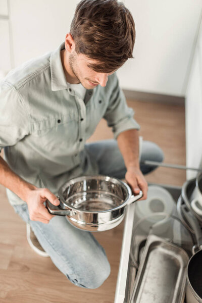 "young man looking at clean dishes in dishwasher"