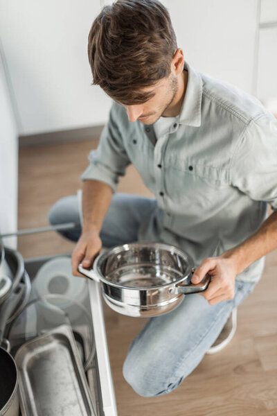 "young man looking at clean dishes in dishwasher"
