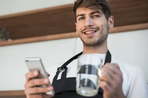 Mutfakta Bir Smartphone Ayakta Ile Gülümseyen Genç Adam — Stok fotoğraf