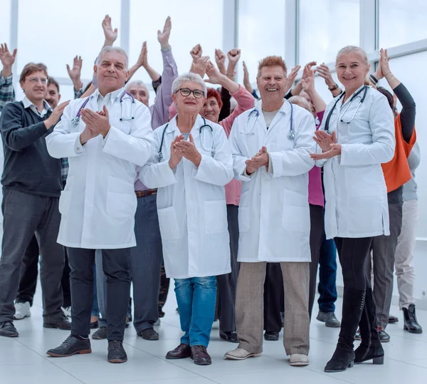 Stock image doctors and a group of mature people applaud