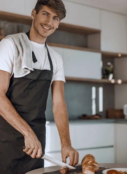 Attractive Young Man Slicing Sausage Sandwiches — Stock Photo, Image
