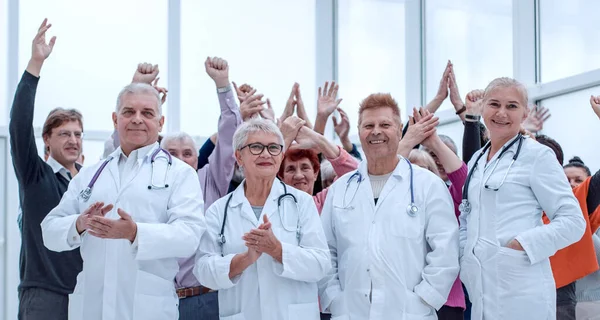 stock image doctors and a group of seniors in full growth indoors hands up