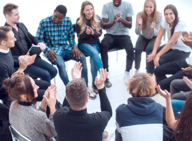 Bir grup seminer katılımcısı bir çemberin içinde otururken alkışlıyor