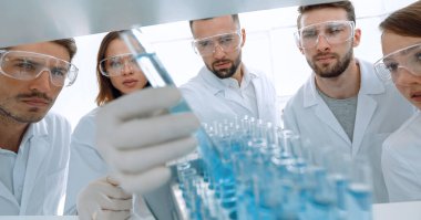 Arkaplan resmi sıvı üzerinde çalışan bir grup mikrobiyologdur. 