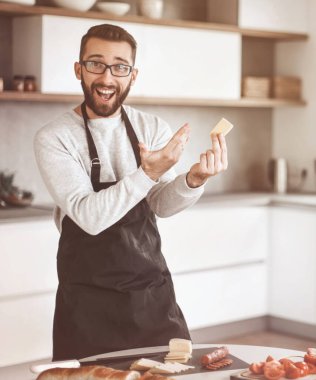 Çekici bir adam lezzetli bir parça peynir gösteriyor.