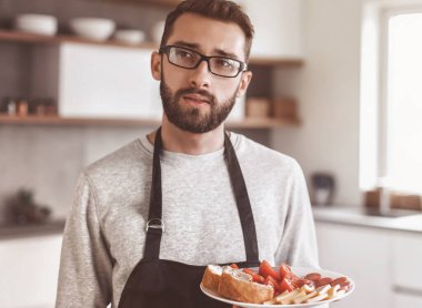 Çekici bir adamın ellerinde bir tabak sandviç.