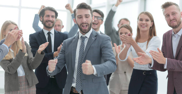 Ликующий молодой бизнесмен принимает поздравления от своей бизнес-команды.