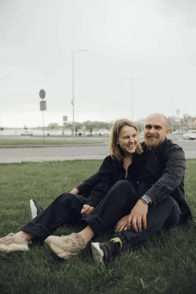 Εραστές Αγκαλιάζουν Κάθεται Στο Γρασίδι Και Εξετάσουμε Την Κάμερα — Φωτογραφία Αρχείου