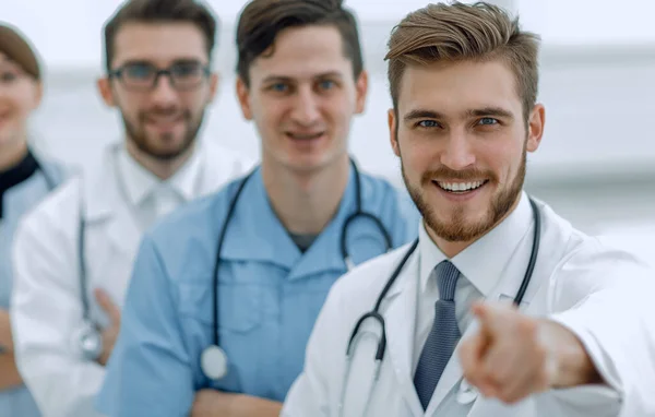 経験豊富な医師が他の医師の背景を指すジェスチャーを示しています — ストック写真