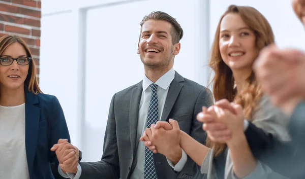Business people in a circle holding hands indoors