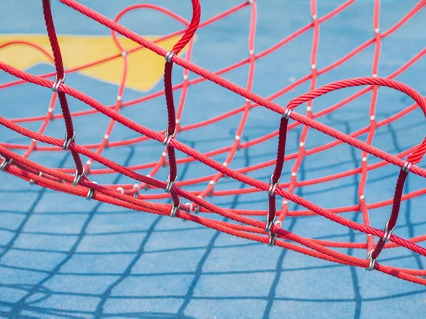 青い背景の赤い網 晴れた日に公共のスポーツ場でスポーツ機器 晴れた日の幾何学的な影 — ストック写真