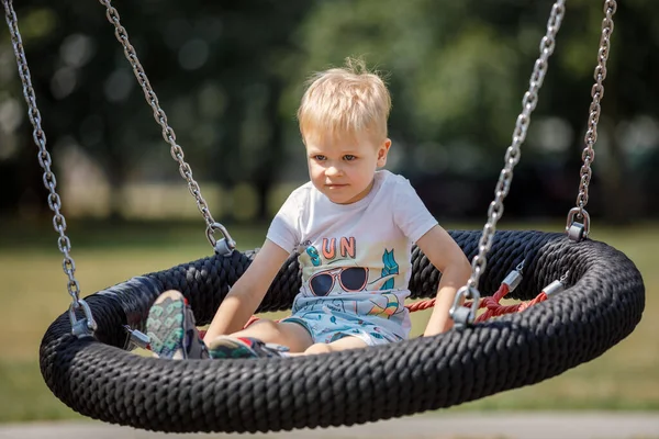 Kis Szőke Fiú Boldogan Játszik Nagy Fészekhintán Városi Játszótéren — Stock Fotó