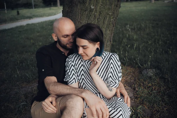 恋人たちは木の下の公園に座って話をしたり抱擁したり — ストック写真