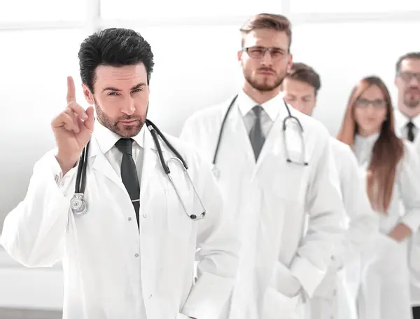 Handsome Young Doctor Lifting His Index Finger His Team Background — Stock Photo, Image