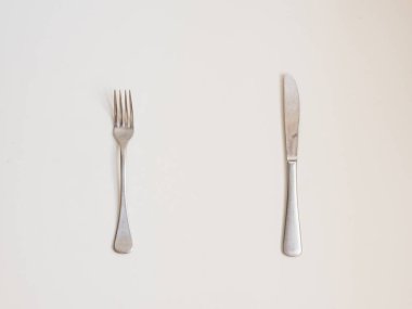 Yiyecek arka planı - beyaz masada çatal ve bıçağın yüksek açılı görüntüsü