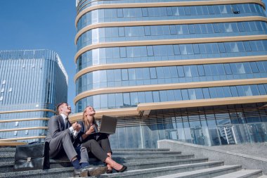 Mutlu şirket çalışanları sokakta dizüstü bilgisayar kullanıyor..