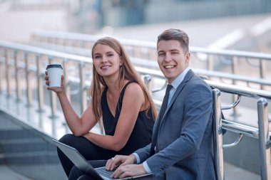 İş çifti ofis binasının yanındaki merdivenlerde oturuyor..