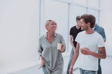ofis koridorundan geçen kahve bardakları ile çalışanlar