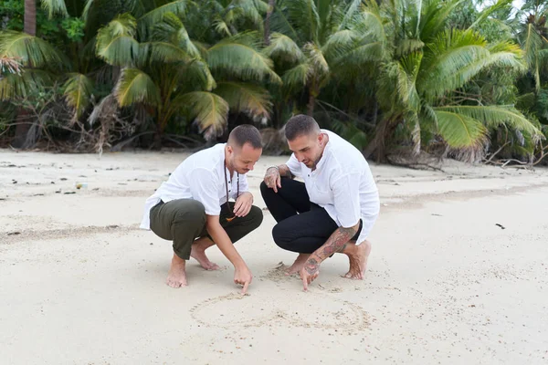 Homoseksüel Erkek Çift Tropik Bir Plajda Kuma Kalp Çiziyor — Stok fotoğraf