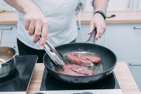 調理教室では フライパンで牛のリビーステーキを調理します スパイスとステーキ 調理プロセス クローズアップ — ストック写真