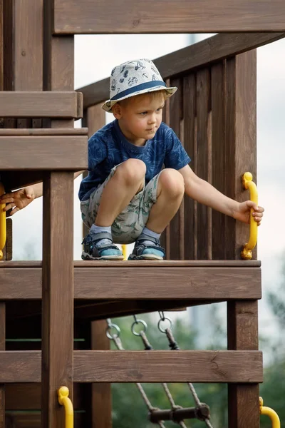 一个头戴白色帽子的小男孩站在一块木头的顶部 观察环境 — 图库照片