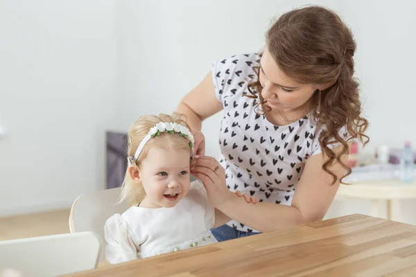 母は小さい女の子の耳に補聴器を屋内に置く彼女の聴覚障害の娘を助ける 難聴の治療における人工内耳と革新的な医療技術 — ストック写真