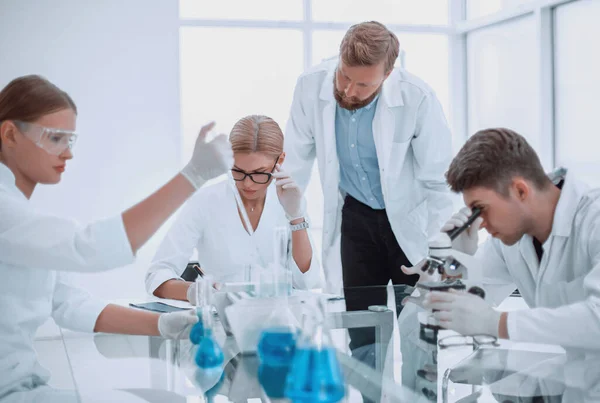 一群坐在实验室桌旁的科学家和医生 — 图库照片