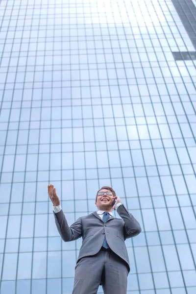 Szczęśliwy Biznesmen Smartfonem Stojącym Przed Budynkiem Biurowym Wysokiego Wzrostu — Zdjęcie stockowe