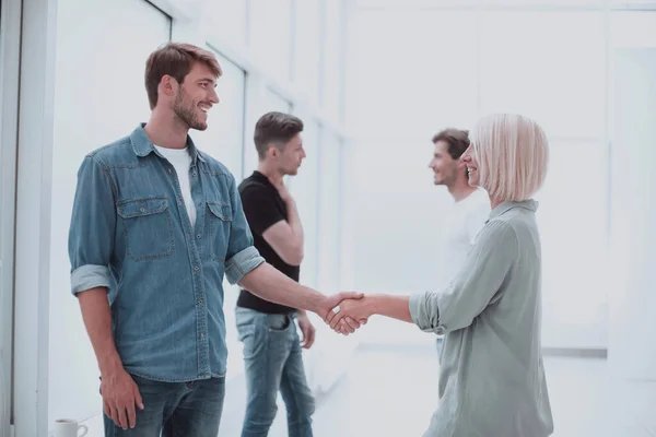 stock image coworkers shaking hands in the office lobby.