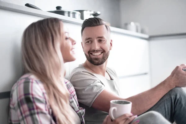 stock image loving couple talking, sitting in the kitchen on the floor