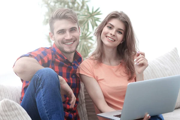 年轻夫妇的学生坐在沙发上的笔记本电脑 — 图库照片