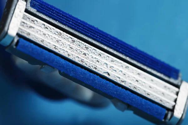 氷水の滴と青の背景にカミソリブレード — ストック写真