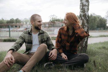 Aşıklar parkta çimlerin üzerinde oturur.